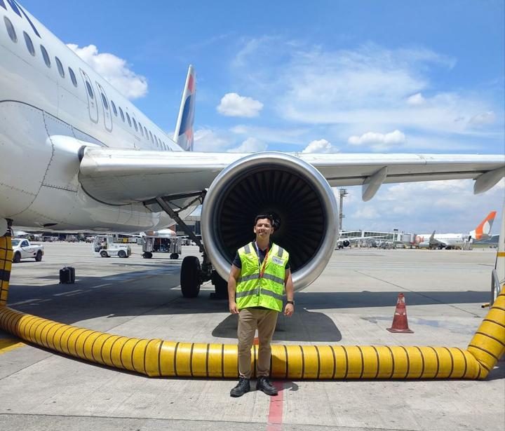 Álvaro con chaleco reflectante frente al motor de un avión en la losa